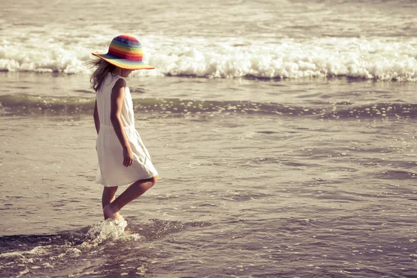 Грустная маленькая девочка, гуляющая по пляжу днем — стоковое фото