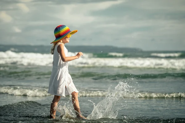 Glückliches kleines Mädchen, das tagsüber am Strand spazieren geht — Stockfoto