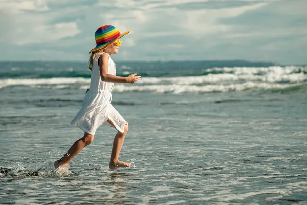 Glückliches kleines Mädchen mit Hut, das am Strand am Tag tim spaziert — Stockfoto