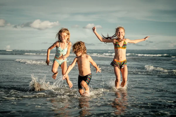 Niños felices jugando en la playa durante el día —  Fotos de Stock