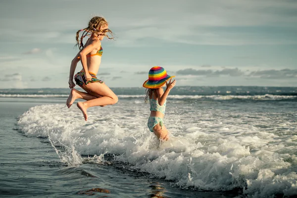在一天的时间在沙滩上溅起的两个姐妹 — 图库照片