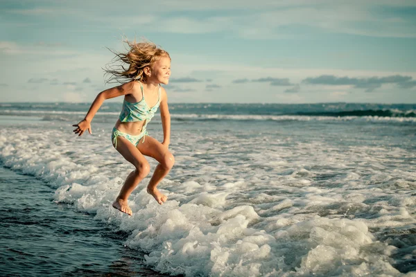 Little girl jumping on the beach in the day time — Stock Photo, Image