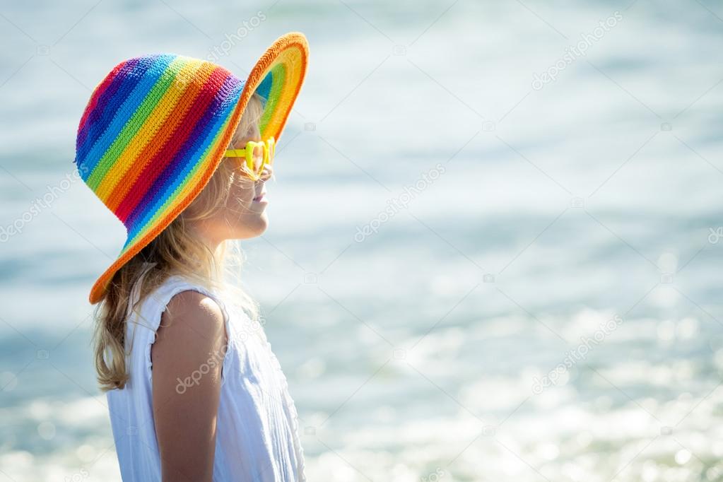 happy little girl in the hat  standing at the beach in the day t