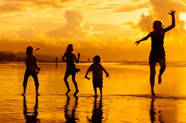 Şafak zamanı kumsalda oynarken mutlu bir aile