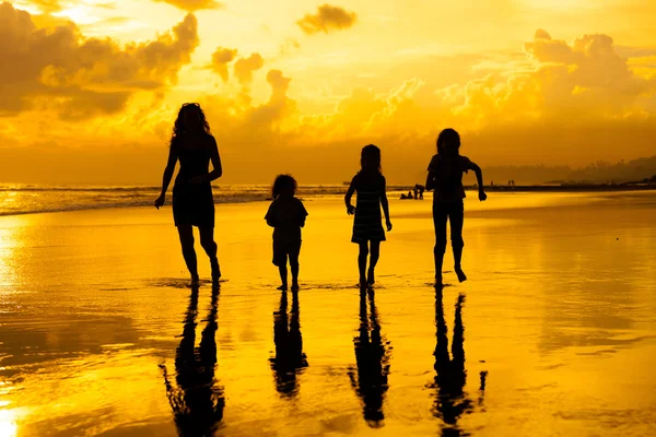 Счастливая семья, играющая на пляже в положенное время — стоковое фото