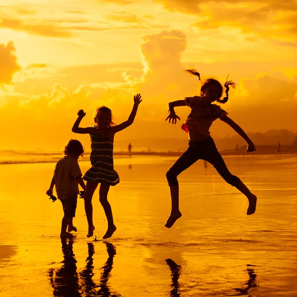 Glückliche Kinder, die im Morgengrauen am Strand spielen — Stockfoto