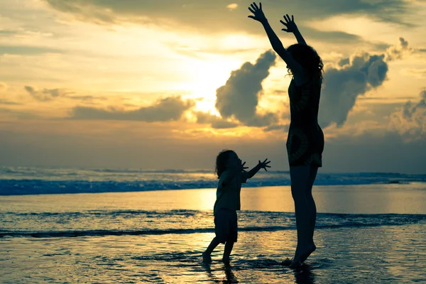 Мать и сын играют на пляже на рассвете — стоковое фото