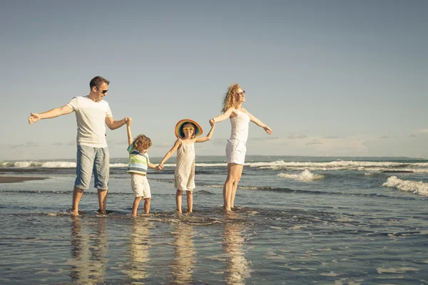 Família feliz brincando na praia durante o dia — Fotografia de Stock