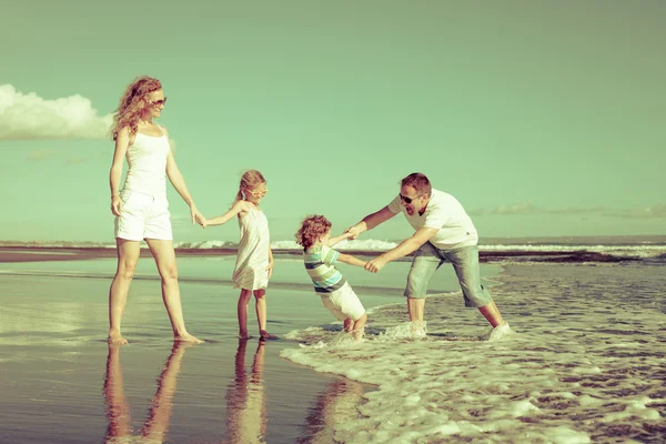 Glückliche Familie spielt tagsüber am Strand — Stockfoto