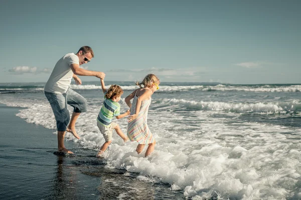 Far, dotter och son spelar på stranden på dagarna — Stockfoto