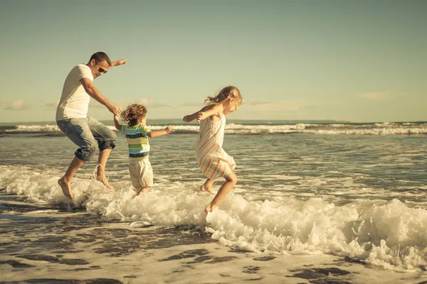 Far, dotter och son spelar på stranden på dagarna — Stockfoto