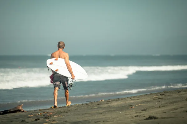 Surfista con tabla camina por la playa —  Fotos de Stock