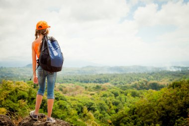 teenager with a backpack standing on a mountain top