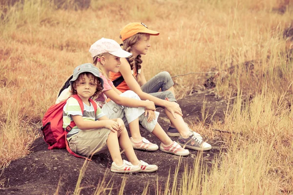 Tre bambini piccoli con zaino seduti sul marciapiede nel m — Foto Stock