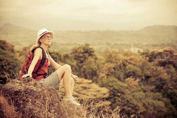 Турист с рюкзаком расслабляясь на скале и наслаждаясь — стоковое фото