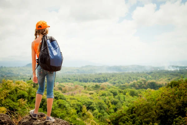 Adolescente com uma mochila em pé no topo de uma montanha — Fotografia de Stock