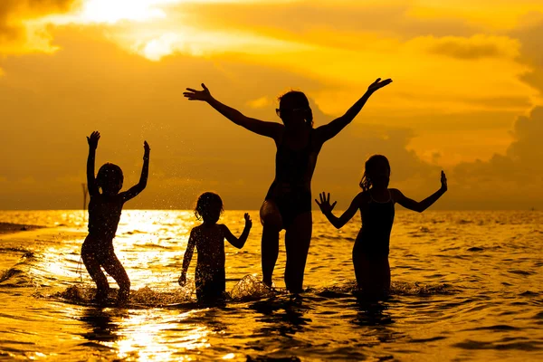 Familia feliz jugando en la playa al amanecer — Foto de Stock