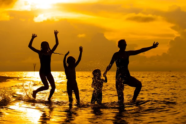 Szczęśliwa rodzina gra na plaży w timeh świt — Zdjęcie stockowe