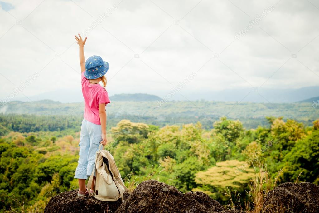 little girl with a backpack on a mountain top