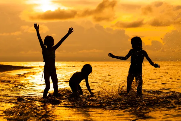 Glückliche Kinder, die im Morgengrauen am Strand spielen — Stockfoto