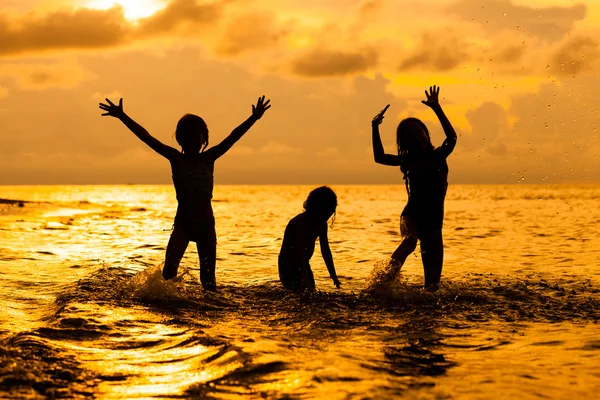 Glada barn som leker på stranden på dawn tiden — Stockfoto