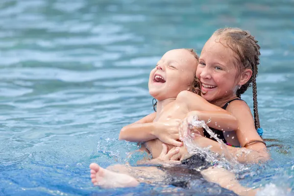 Broer en zus spelen in het zwembad — Stockfoto