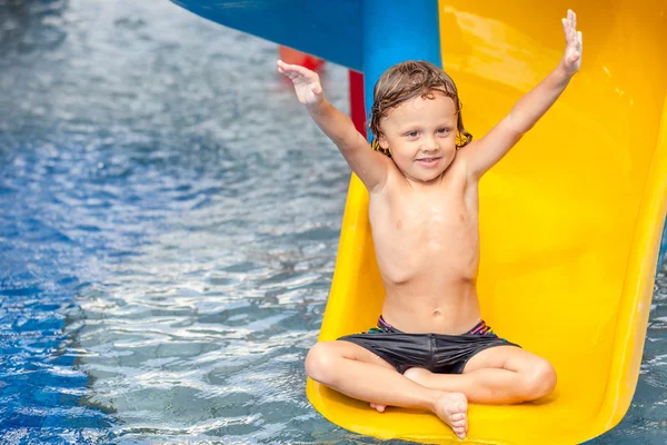 Kleiner Junge spielt im Schwimmbad auf Rutsche — Stockfoto