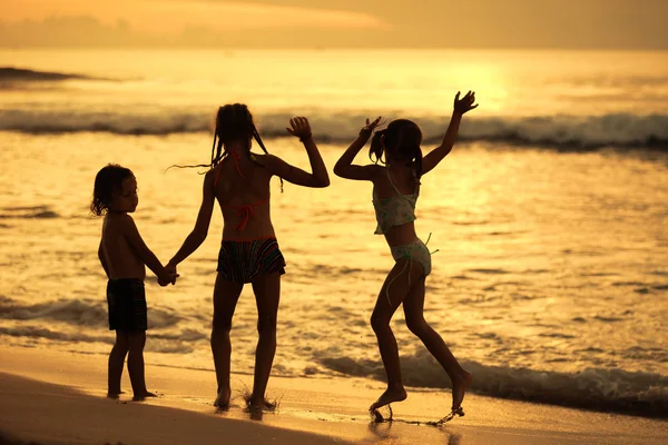 Glada barn spela på stranden med dawn — Stockfoto