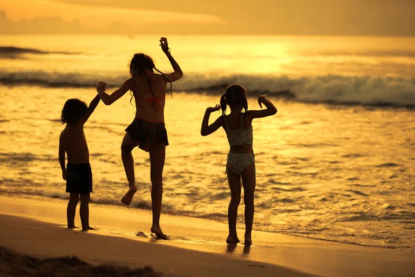 Glada barn spela på stranden med dawn — Stockfoto