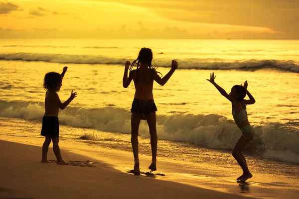 Счастливые дети, играющие на пляже в назначенное время — стоковое фото