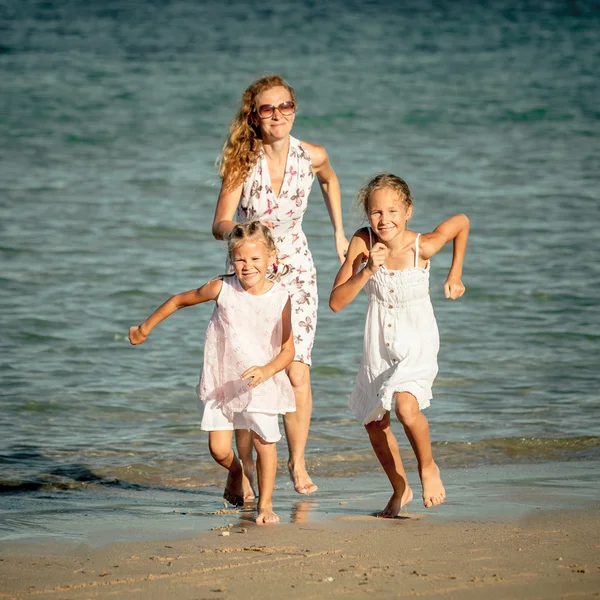 Familia feliz corriendo en la playa durante el día — Foto de Stock