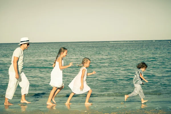 Familia feliz corriendo en la playa durante el día — Foto de Stock