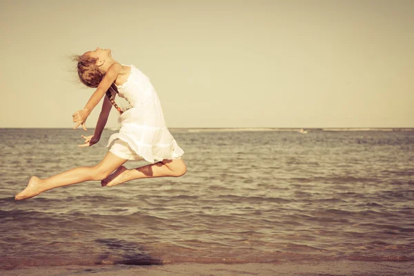 Tiener meisje springen op het strand op het moment van de dag — Stockfoto