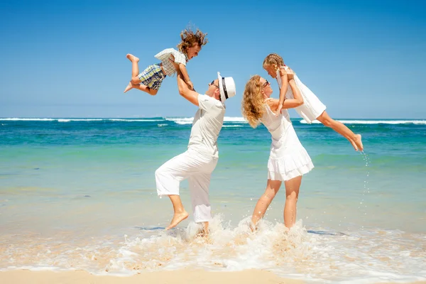 Família feliz brincando na praia na hora do dia — Fotografia de Stock