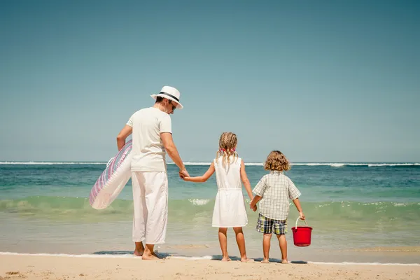 Lyckliga familjen promenerar på stranden på dagarna — Stockfoto