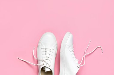 Pembe arka planda beyaz kadın deri spor ayakkabıları düz yerde yatıyordu. Şık gençlik ayakkabıları, spor ayakkabıları, hakiki deri ayakkabılar. Minimalist ayakkabı mağazası reklamcılığı moda ayakkabısı arka planı.