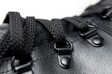 Beyaz arka planda siyah deri sonbahar çizmeleri vardı. Şık kadınların erkek üniformaları. Ayakkabı bağcıklı Grunge botları. Kıyafetler, ayakkabılar, moda geçmişi. Klasik deri ayakkabılar..