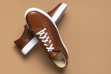 Deri kahverengi erkek ayakkabıları, beyaz bağcıklar ve bej arka planda lastik tabanlar. Düz manzaralı. Erkek spor ayakkabıları. Modaya uygun spor ayakkabılar. Erkek modası hipster ayakkabı geçmişi çok düşük..