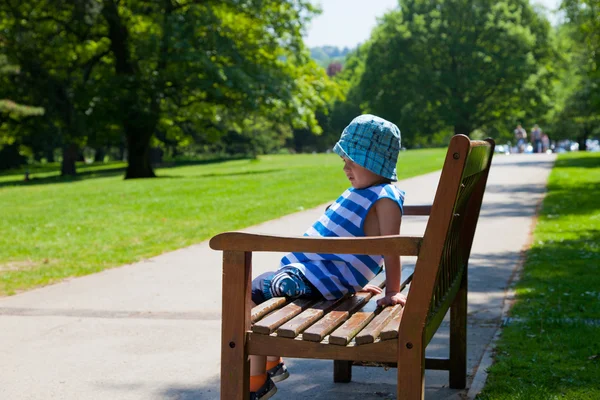 Niño en el banco en el parque —  Fotos de Stock