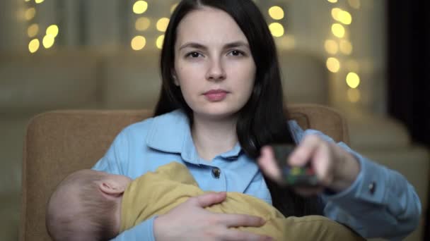 Ibu dengan anak yang baru lahir menonton televisi di rumah. — Stok Video
