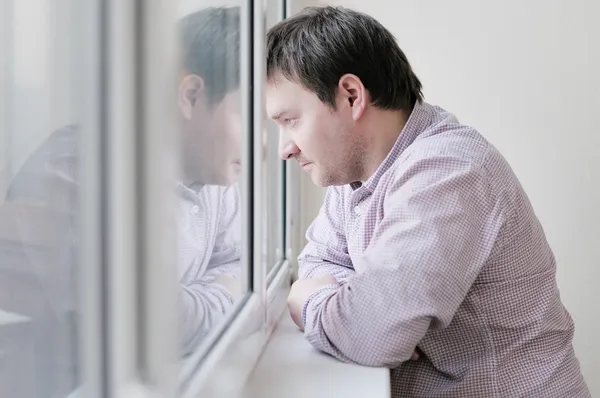Мужчина смотрит в окно Лицензионные Стоковые Фото