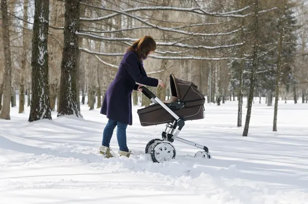Woman walking with baby carriage — Stock Photo, Image