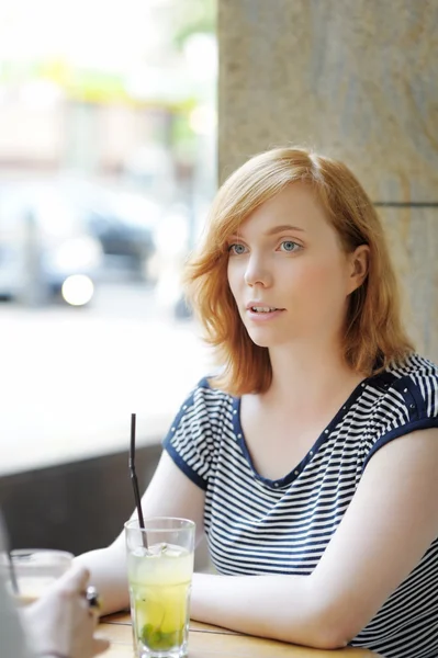 Jonge vrouw in een openlucht café — Stockfoto