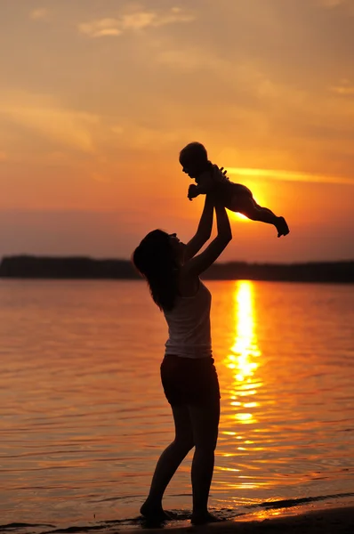 Frau mit kleinem Baby als Silhouette am Wasser — Stockfoto