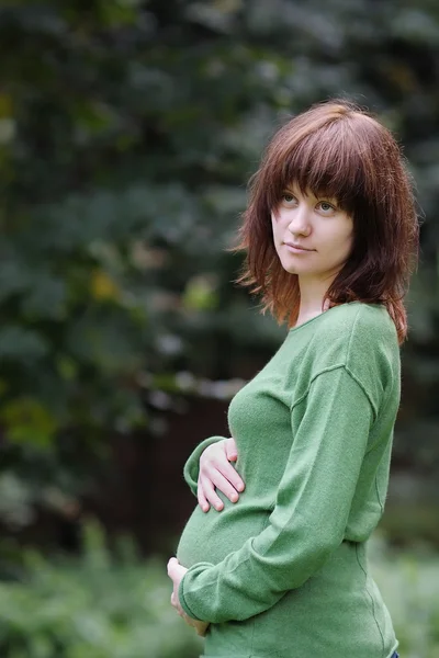 Vrouw hand in hand op haar zwangere buik — Stockfoto