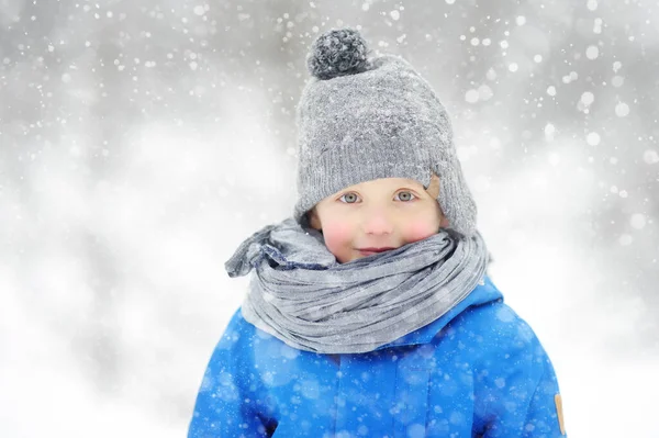 一个穿着蓝色冬衣的滑稽小男孩在雪地里散步的画像 可爱的孩子穿着温暖的衣服 戴着帽子 戴着围巾看着你 有子女家庭的户外活动 — 图库照片