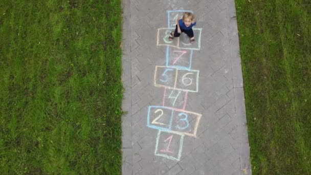 Luchtfoto Van Kleine Jongen Springen Door Hopscotch Getrokken Asfalt Kind — Stockvideo