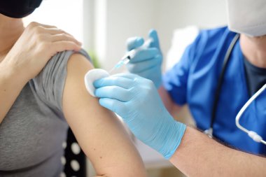 Doctor or nurse is preparing to give a injection vaccine against covid-19 to a woman. Mass vaccination of the population will help stop spread of coronavirus in the world. Herd immunity