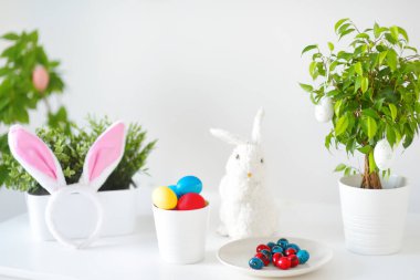 Renkli yumurtalar, şirin küçük tavşanlar ve Paskalya günü masanın üstünde tavşan kulakları. Baharda Paskalyayı kutluyoruz. Yumurta boyamak. Tatil için ev dekorasyonu.
