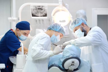 Diş ameliyatı sırasında cerrah ve hemşire. Anestezi yapılmış hasta ameliyathanede. Diş implantı ya da diş çıkarma kliniğine yerleştirilmiş. Ortodonti ameliyatı sırasında genel anestezi..